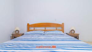 a bed with a blue and white striped comforter and two lamps at Casa Aconchegante em Bertioga a 700m da Praia in Bertioga