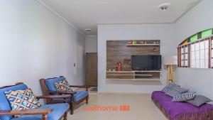 a living room with two blue chairs and a tv at Casa Aconchegante em Bertioga a 700m da Praia in Bertioga