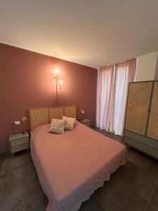 a bedroom with a pink bed with two pillows on it at Alloggi CH40 in Imperia