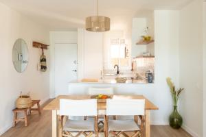 una cucina con un tavolo di legno e sedie bianche di Precioso apartamento en Platja d'Aro, Costa Brava. a Platja  d'Aro Altre 8 foto