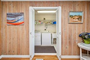 a kitchen with white appliances and wooden walls at Late For The Sky by Oak Island Accommodations in Caswell Beach +133 photos