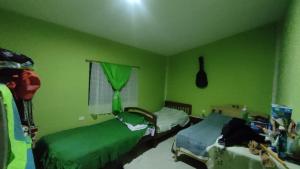 a green bedroom with two beds and a window at ChocoTown in Puerto Quito