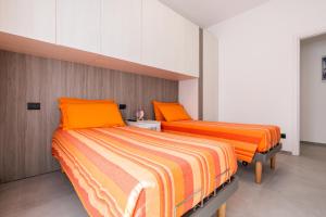 two beds in a room with orange pillows at Casa Blue Moon in Baveno