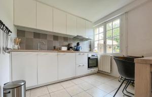 a kitchen with white cabinets and a black chair at Amazing Home In Saint Pons La Calm in Saint-Pons-la-Calm
