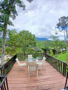 a wooden deck with a table and chairs on it at Grace Hill Villa Lubuk Minturun in Padang