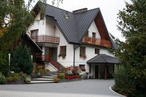 a large white house with a black roof at Wiśniowy Gaj in Ujanowice