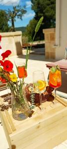 a wooden table with two glasses and flowers on it at Massì bnb in Locorotondo