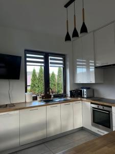 a kitchen with white cabinets and a sink and a window at Domek Orłówka in Jaworzna +8 photos