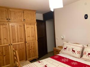 Un dormitorio con una cama y armarios de madera. en Appartamento Le Marmotte - Auronzo, en Auronzo di Cadore
