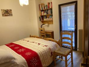 Un dormitorio con una cama y una silla y una ventana. en Appartamento Le Marmotte - Auronzo, en Auronzo di Cadore