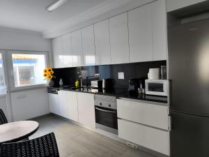 a kitchen with white cabinets and a black and white appliances at Baleal 4 Surf II in Baleal