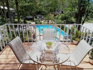 a glass table and four chairs on a deck at Grace Hill Villa Lubuk Minturun in Padang