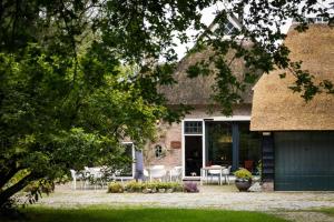 a house with tables and chairs in front of it at Landgoed Getafix in Balkbrug