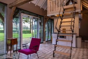 a living room with a staircase and a purple chair at Landgoed Getafix in Balkbrug