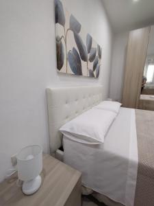 Un dormitorio blanco con una cama y una mesa. en Manenti Holiday House, en Noto