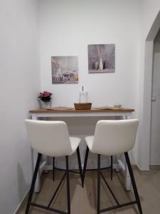 two white chairs and a table in a room at Manenti Holiday House in Noto +3 photos