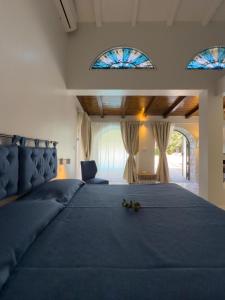 a bedroom with a large bed with blue sheets and stained glass windows at B&B La Villa in Giardini Naxos
