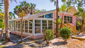 a pink house with palm trees in front of it at Little Palm Cottage in Sanibel