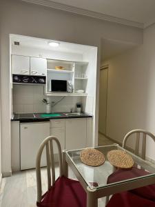 a kitchen with a table and chairs and a microwave at Hospedium Hotel Apartamentos Simón Verde in Mairena del Aljarafe