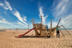 two people standing next to a playground on the beach at Vos vacances à la mer in Valras-Plage