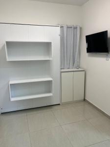 a white refrigerator with shelves and a television in a room at Studio privativo com Ar condicionado in Lauro de Freitas