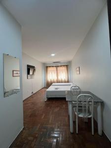 a bedroom with a bed and a table and chairs at Apartamento 111 - Suíte econômica com ar condicionado in Patos de Minas