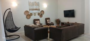 Una sala de estar con sofás y un televisor de pantalla plana. en Khaya Apartments Victoria Falls Estate, en Victoria Falls