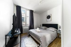 a white bedroom with a bed and a television at Résidence Gilbert - Appartements design centre ville in Vichy