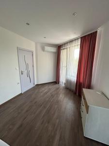 ein leeres Wohnzimmer mit einem roten Vorhang in der Unterkunft Денерис in Dobritsch + 12 Fotos