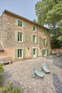 two chairs and a building with green shutters at Bastide entièrement rénovée au coeur de Goult in Goult