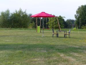 a red umbrella and two chairs in a park at Gites Domaine de la Rochere in Domsure