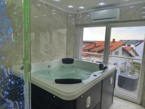 a bathroom with a tub with a large window at Villa Vlasta in Soko Banja