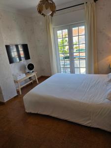 a bedroom with a large white bed and a window at Soleil Bleu in Vila Nova de Milfontes
