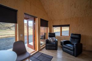 a living room with two chairs and windows at Paradise Cottages in Vík