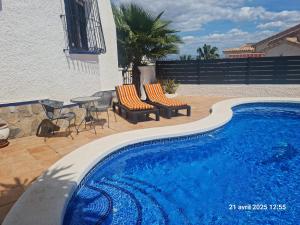 a swimming pool with chairs and a table next to a building at casa des loups in Ciudad Quesada