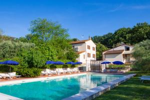 a swimming pool with chairs and umbrellas next to a house at Agriturismo La Serra in Cenaia