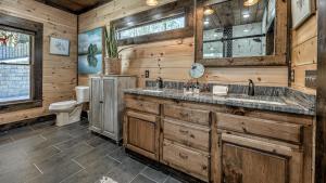a bathroom with two sinks and a toilet in a log cabin at Jazzy's Cozy Creekside in Blue Ridge +59 photos