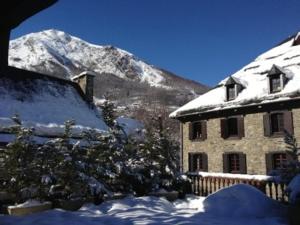 ein schneebedecktes Gebäude mit einem Berg im Hintergrund in der Unterkunft Appartement La Foncière in Saint-Lary-Soulan