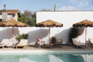a group of chairs and umbrellas next to a pool at Villa Réal in Saint-Seurin-de-Cadourne +27 photos