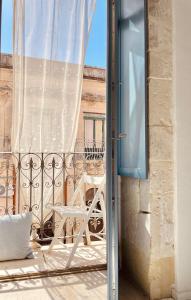 Un balcón con una silla blanca y una ventana en Vittorio Veneto by Bed&Bros, en Siracusa