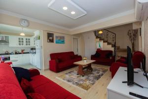 a living room with red furniture and a kitchen at Villa carin in Ortaca