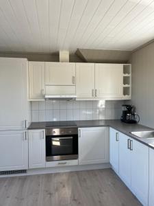 a white kitchen with white cabinets and a stove at Sjåen Panorama in Kragerø