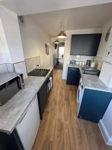 a kitchen with blue and white counters and wooden floors at Beautiful furnished 2 bed flat in Colchester
