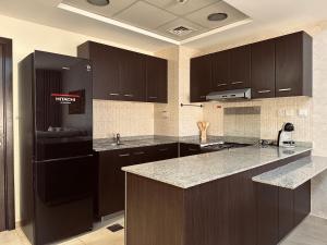 迪拜Elegant Family Stay - Playground View in Remraam的配有黑色橱柜和台面的厨房