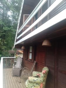 a porch with two chairs and a lamp at Casa no Bosque Vila Natal in Campos do Jordão