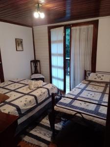 two beds in a room with a window at Casa no Bosque Vila Natal in Campos do Jordão