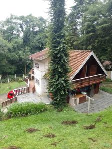 a small house with a tree in front of it at Casa no Bosque Vila Natal in Campos do Jordão