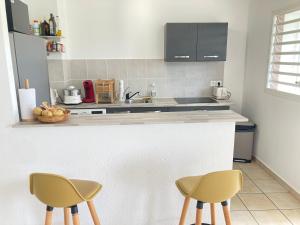 a kitchen with two chairs sitting at a counter at Charme Vanillé 2 chambres avec piscine et parking Gosier 5 min plage in Le Gosier