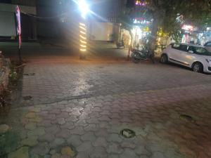a cobblestone street at night with cars parked at Hotel Coral in Indore
