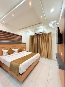 ein Schlafzimmer mit einem großen Bett und einem Fernseher in der Unterkunft Stay Bridge Residency in Kozhikode